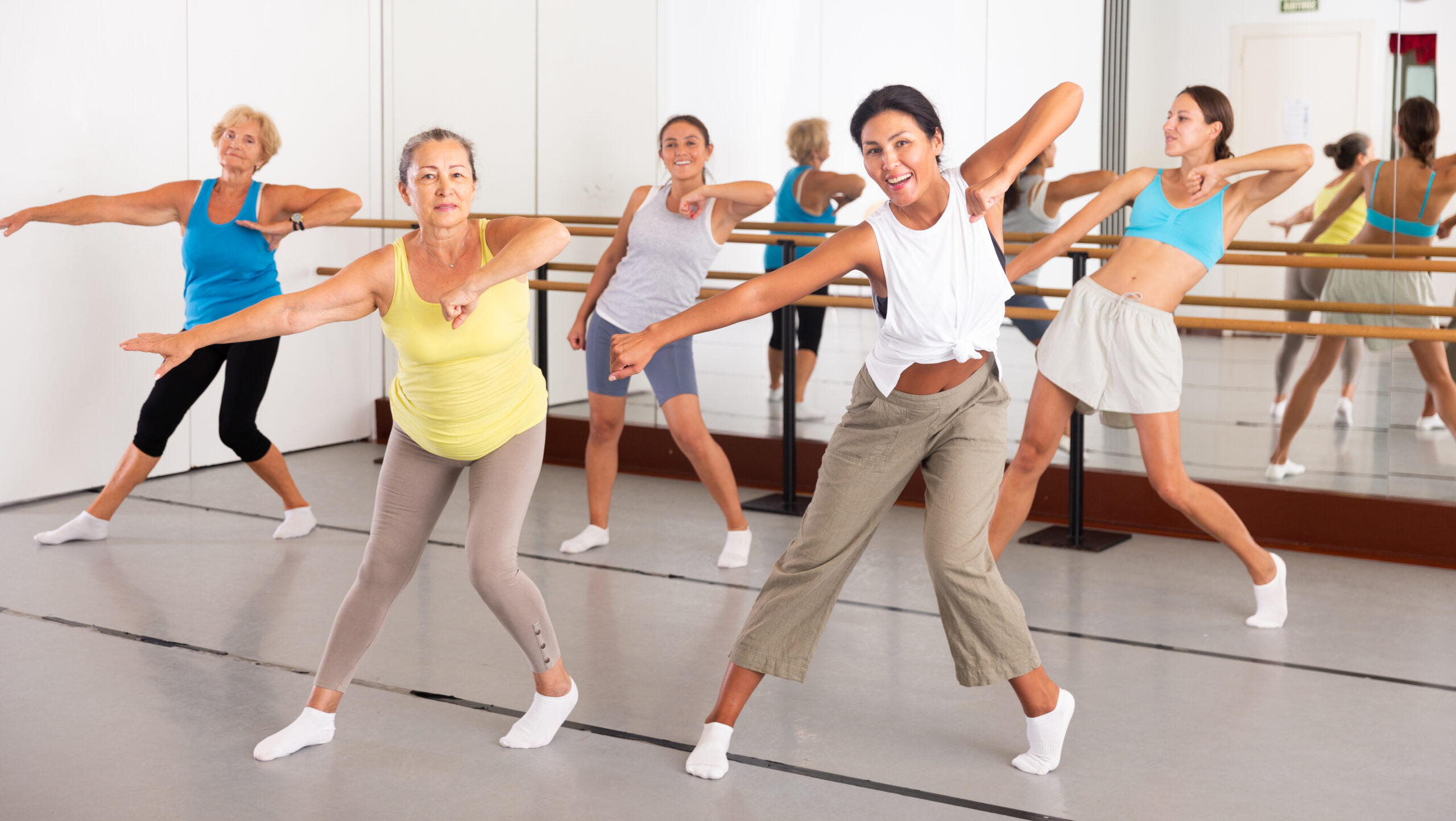 Group of various aged women dancing modern dance in studio.